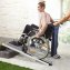 Rollstuhlfahrerin fährt über eine Rollstuhlrampe die Treppe hoch